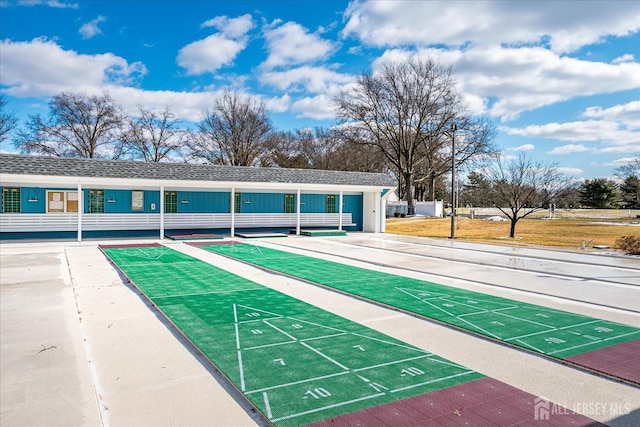 view of community featuring a yard, fence, and shuffleboard