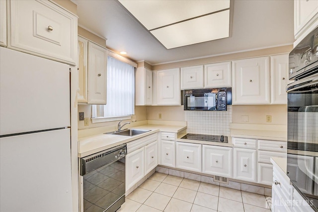 kitchen with a sink, white cabinets, black appliances, and light countertops