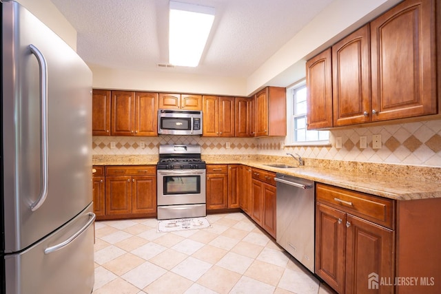 85 W Shrewsbury Pl, Princeton, NJ 08540 - kitchen with appliances with stainless steel finishes, a sink, brown cabinetry, tasteful backsplash, and a textured ceiling