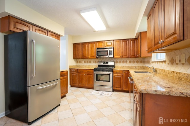 85 W Shrewsbury Pl, Princeton, NJ 08540 - kitchen with appliances with stainless steel finishes, a sink, brown cabinetry, backsplash, and light stone countertops