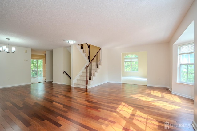 85 W Shrewsbury Pl, Princeton, NJ 08540 - unfurnished living room featuring hardwood / wood-style floors, a textured ceiling, a chandelier, and healthy amount of natural light