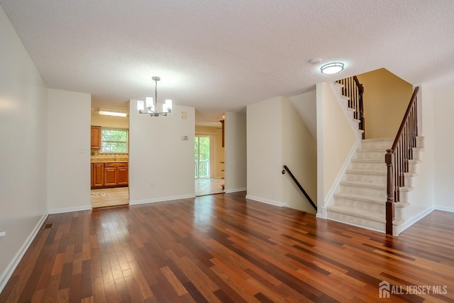 85 W Shrewsbury Pl, Princeton, NJ 08540 - unfurnished living room featuring dark wood-type flooring, a chandelier, a textured ceiling, stairs, and baseboards