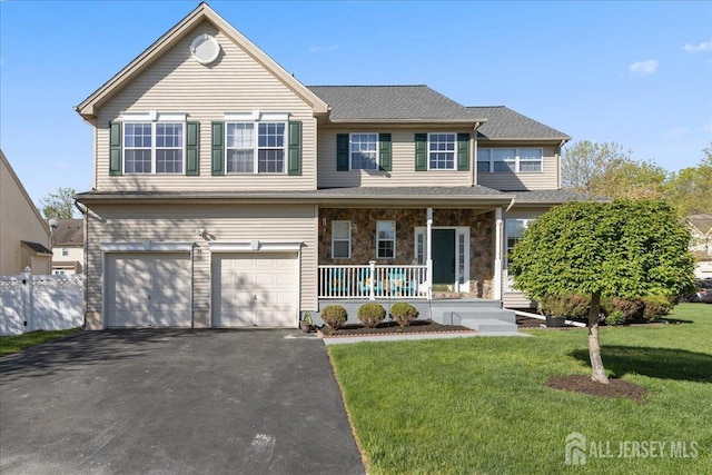 traditional home featuring covered porch, driveway, a front yard, a garage, and fence