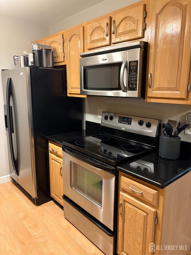kitchen featuring appliances with stainless steel finishes, dark countertops, and light wood finished floors