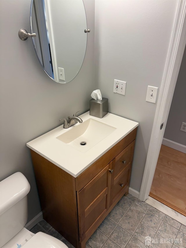 half bath with vanity, toilet, and baseboards