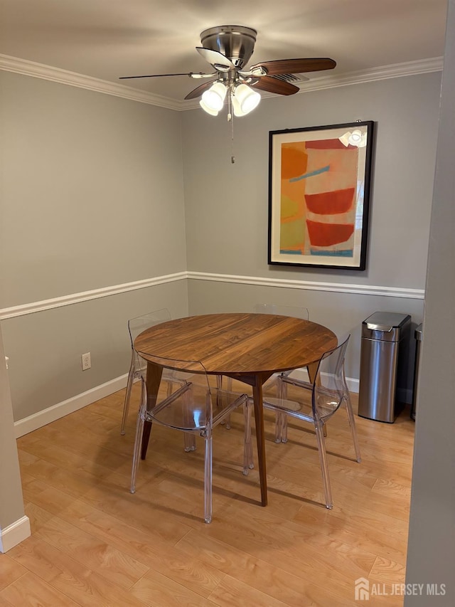 dining space featuring ceiling fan, ornamental molding, light wood finished floors, and baseboards