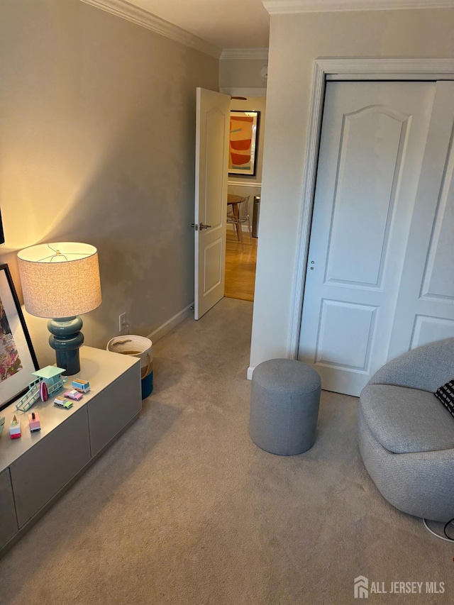 sitting room with ornamental molding, carpet floors, and baseboards