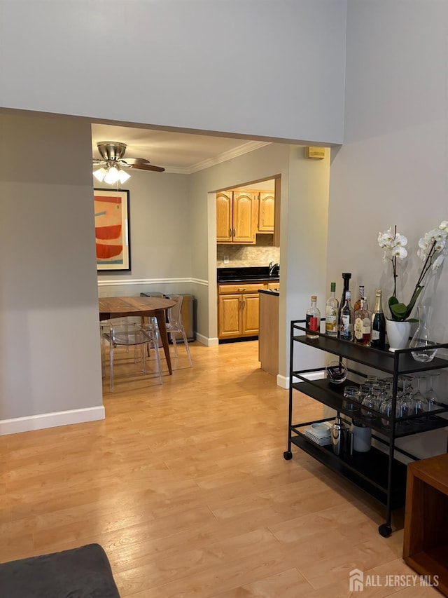 corridor with crown molding, light wood finished floors, and baseboards