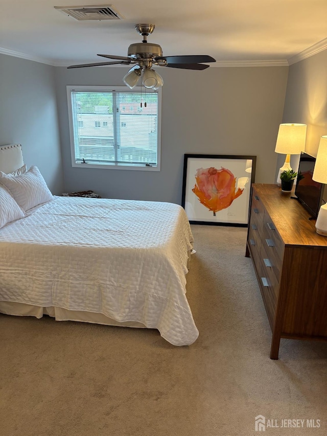 carpeted bedroom with ornamental molding and a ceiling fan