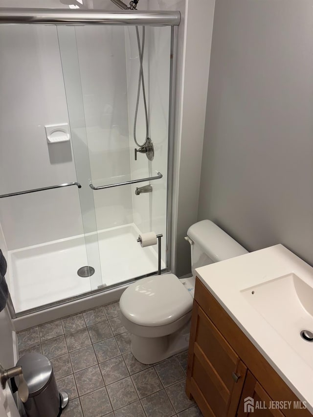 full bathroom featuring a stall shower, toilet, and vanity