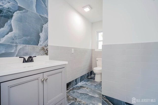 2 Buttonwood Dr, Parlin, NJ 08859 - bathroom featuring tile walls, marble finish flooring, toilet, a wainscoted wall, and vanity