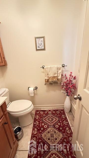 bathroom featuring vanity, tile patterned flooring, toilet, and baseboards