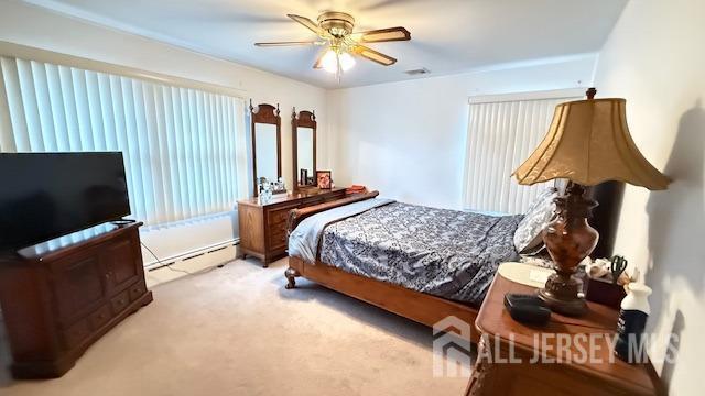 bedroom featuring a baseboard heating unit, carpet floors, and a ceiling fan