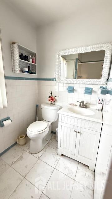 bathroom with vanity, toilet, and tile walls