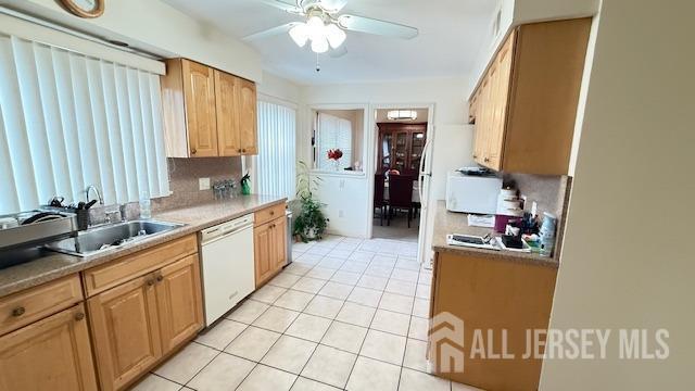 kitchen with light tile patterned floors, backsplash, ceiling fan, a sink, and white appliances