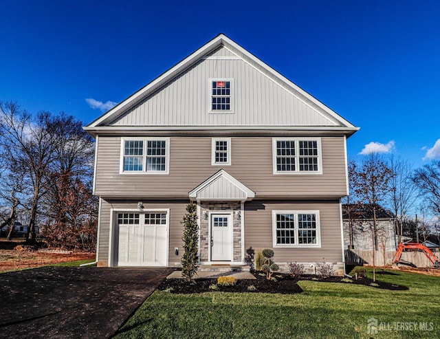 colonial inspired home with aphalt driveway, an attached garage, and a front yard