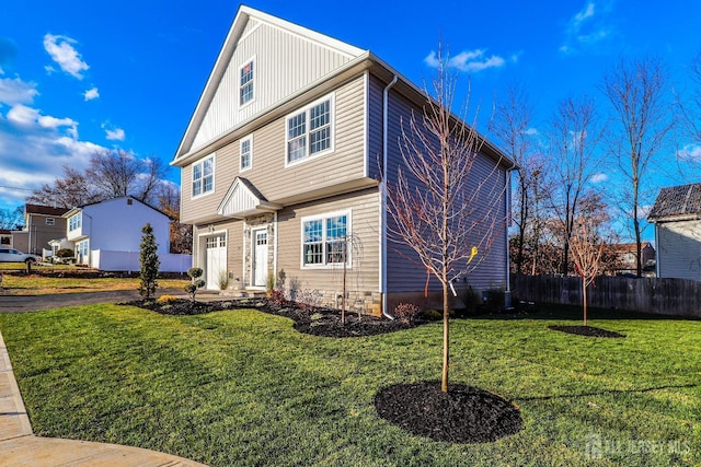 view of front of house with a garage, board and batten siding, a front lawn, and fence