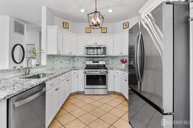 16 Exeter Pass, Colts Neck, NJ 07722 - kitchen with appliances with stainless steel finishes, a sink, a chandelier, white cabinetry, and decorative backsplash