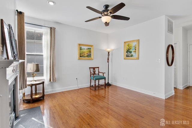 16 Exeter Pass, Colts Neck, NJ 07722 - sitting room featuring ceiling fan, light wood-style flooring, a glass covered fireplace, and baseboards