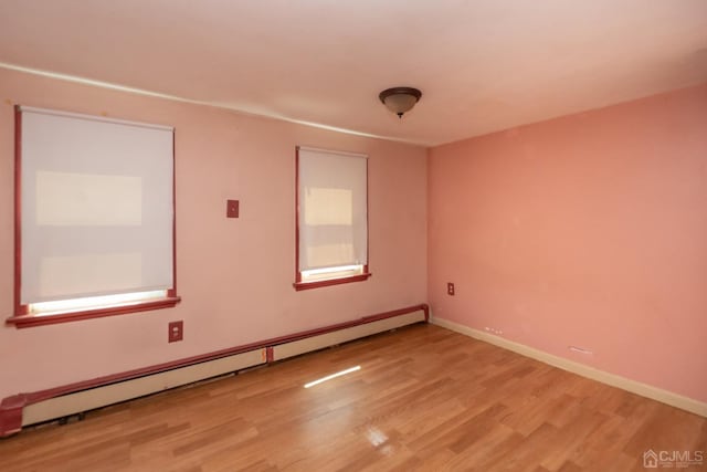 empty room featuring baseboard heating and light hardwood / wood-style flooring