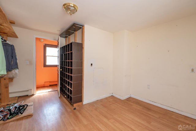 empty room with light wood-type flooring and a baseboard heating unit