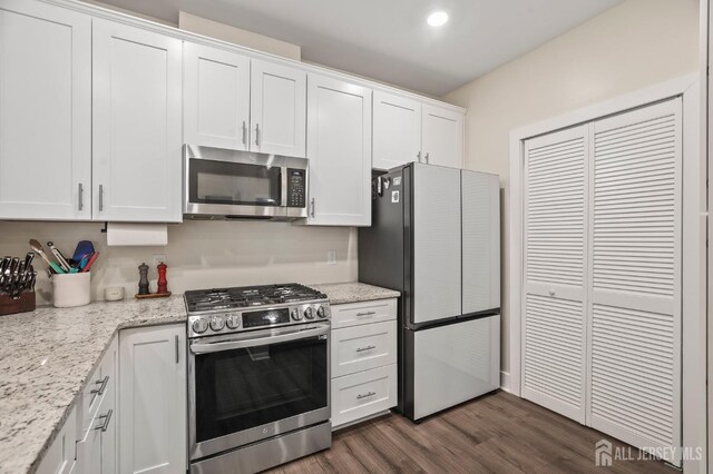 kitchen featuring light stone countertops, stainless steel appliances, dark hardwood / wood-style floors, and white cabinets