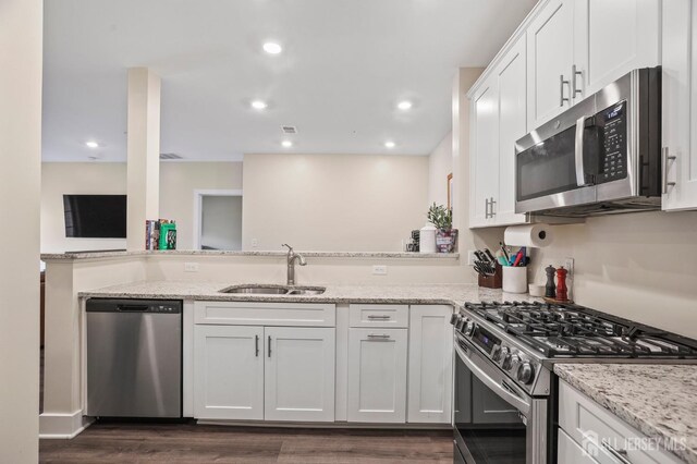 kitchen featuring appliances with stainless steel finishes, light stone countertops, sink, and white cabinets