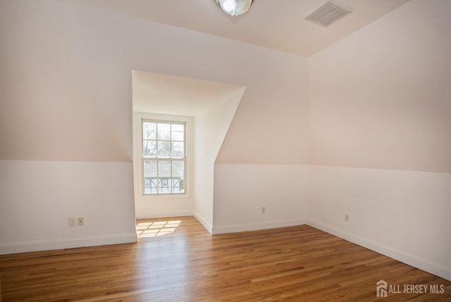 bonus room featuring lofted ceiling, wood finished floors, visible vents, and baseboards