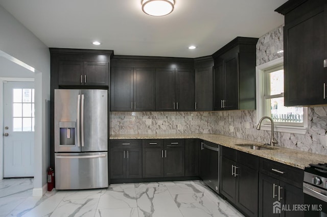 kitchen featuring light stone counters, a sink, decorative backsplash, appliances with stainless steel finishes, and marble finish floor