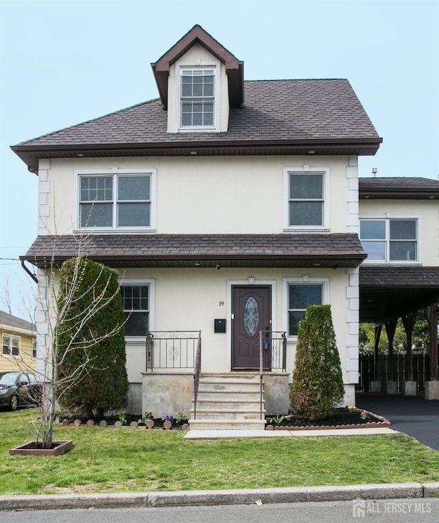 traditional style home with aphalt driveway, a shingled roof, stucco siding, a carport, and a front lawn