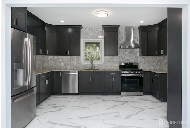 kitchen with light stone countertops, marble finish floor, stainless steel appliances, wall chimney exhaust hood, and a sink