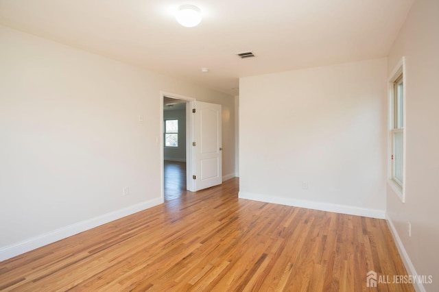 empty room featuring light wood-type flooring, baseboards, and visible vents