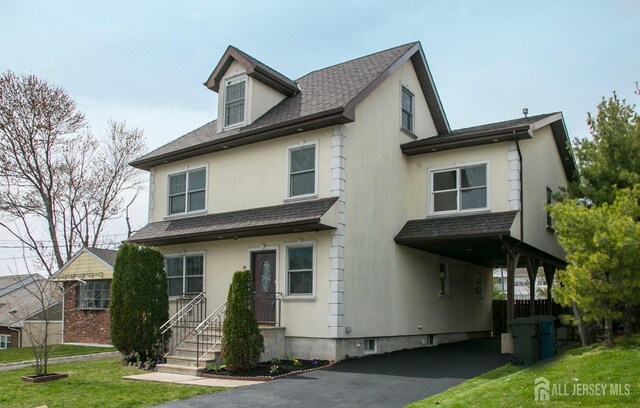 view of front of home with a shingled roof, aphalt driveway, a front lawn, a carport, and stucco siding