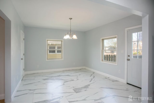 unfurnished dining area with a notable chandelier, marble finish floor, and baseboards