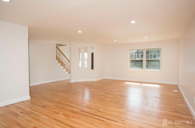 empty room featuring recessed lighting, stairway, baseboards, and light wood finished floors