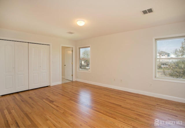 unfurnished bedroom featuring light wood-style floors, visible vents, and baseboards