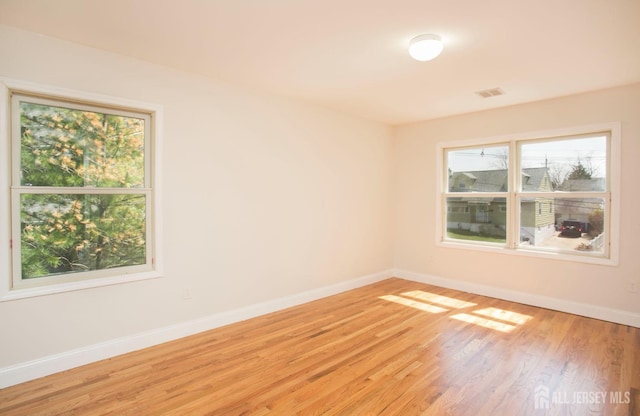 unfurnished room featuring visible vents, baseboards, and light wood-style floors