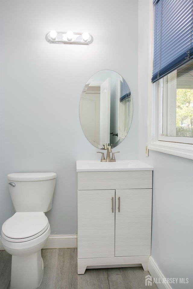 bathroom with baseboards, toilet, wood finished floors, and vanity