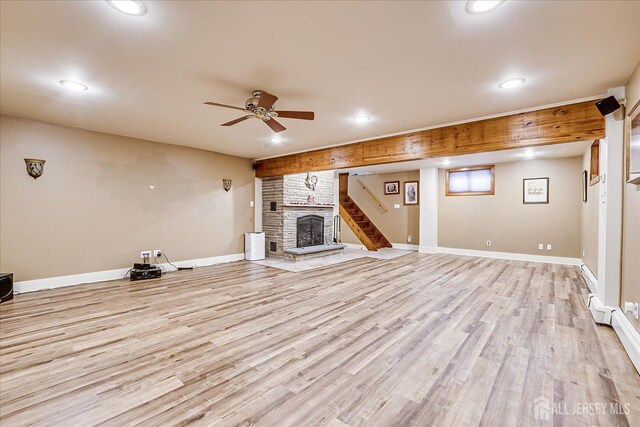 unfurnished living room with ceiling fan, a brick fireplace, a baseboard heating unit, and light hardwood / wood-style floors