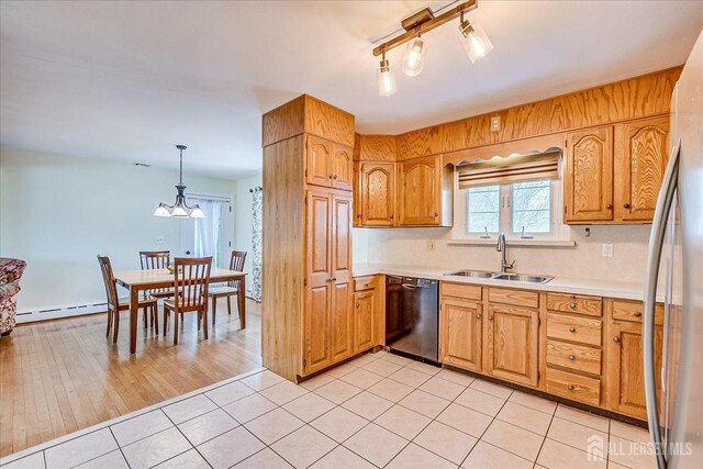 kitchen with dishwasher, decorative light fixtures, a baseboard heating unit, sink, and light tile patterned floors