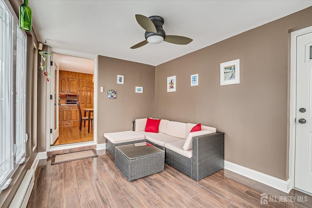 living room with wood-type flooring, a baseboard radiator, and ceiling fan