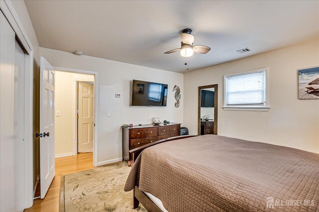 bedroom with ceiling fan, light hardwood / wood-style floors, and a closet