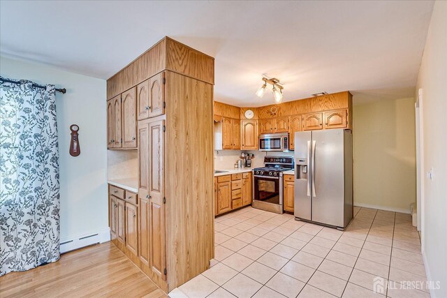 kitchen featuring light tile patterned floors, baseboard heating, and appliances with stainless steel finishes