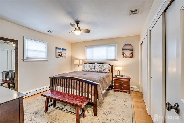 bedroom featuring light wood-type flooring, ceiling fan, and baseboard heating