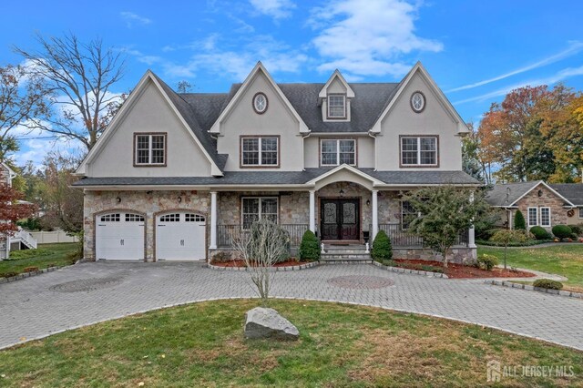 view of front of property with a garage, covered porch, and a front lawn