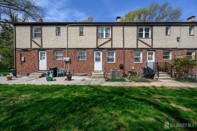 245 Newman St, Metuchen, NJ 08840 - back of house featuring a chimney, cooling unit, a lawn, and stucco siding