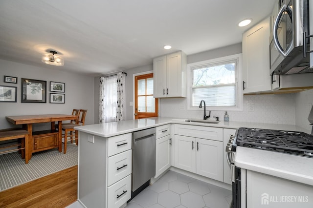 245 Newman St, Metuchen, NJ 08840 - kitchen with appliances with stainless steel finishes, a sink, a peninsula, light countertops, and white cabinets