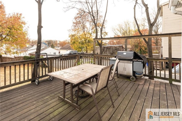 wooden deck featuring outdoor dining area, a grill, and fence