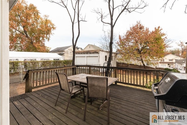 deck featuring outdoor dining space, a grill, fence, and an outdoor structure