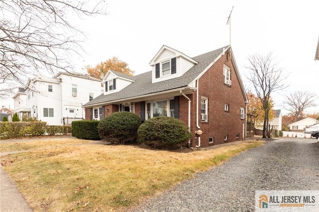 new england style home featuring brick siding and a front lawn